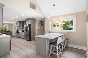 A modern kitchen with a central island, stainless steel appliances, and a view of the garage through a large window.