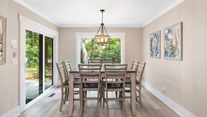 A dining area with a table and chairs, a chandelier, and artwork on the walls. - Spacious, Pet-Friendly Home  Sea Pines Golf Views (Hilton Head Island)