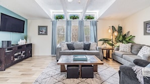 Un salon comprenant un ensemble de canapés, une table basse, un téléviseur et un ventilateur de plafond.