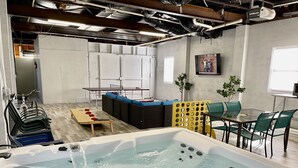Une pièce équipée d’un jacuzzi, d’une table de ping-pong et d’un coin salon avec des chaises et une table.