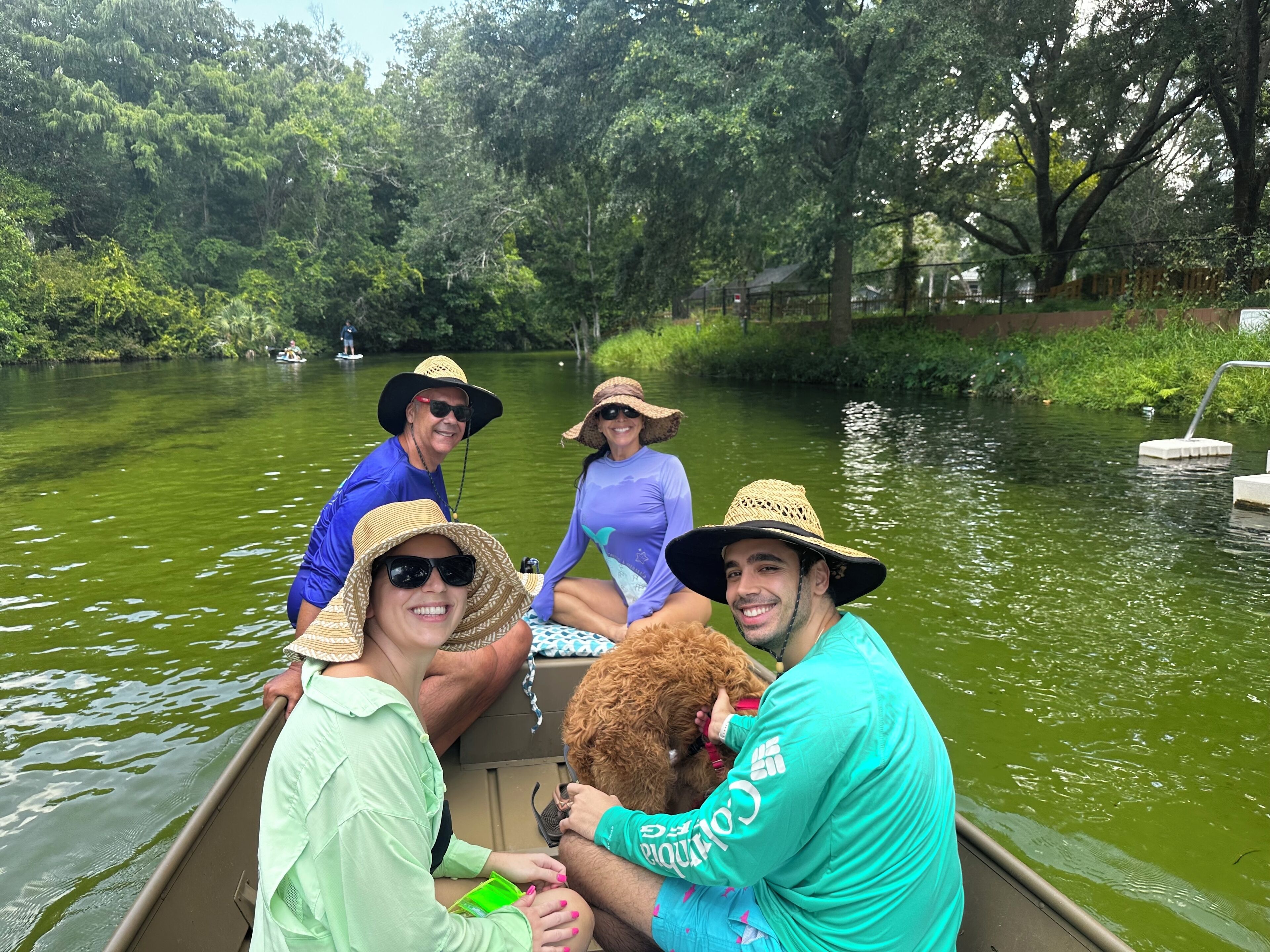 A group of people in a boat on a river surrounded by greenery.