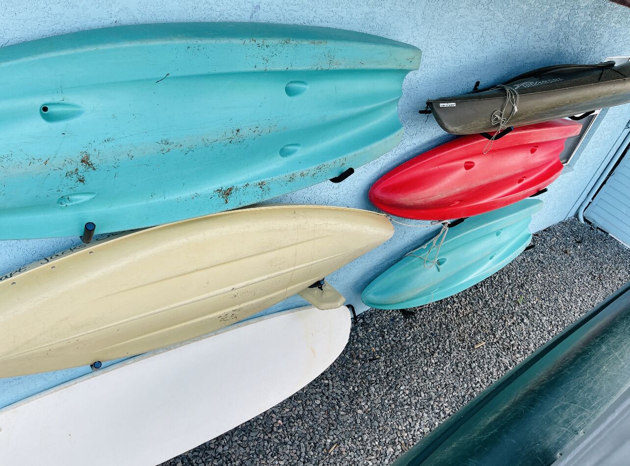 A row of kayaks leaning against a wall.