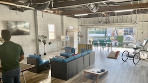 Un salon moderne avec une table de ping-pong, des sièges confortables, une grande fenêtre offrant une belle vue et un vélo posé dans un coin.