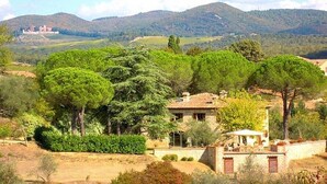 A rustic villa with a stone facade, surrounded by lush greenery and hills in the background. - Podere Lucignano Secondo - La Mangiatoia (Gaiole in Chianti)