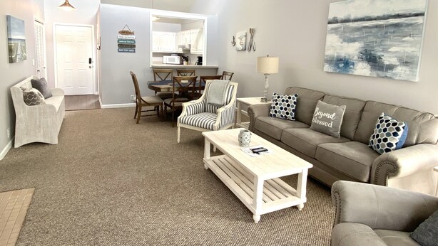 A spacious living room with a high ceiling, a dining area with wooden furniture, and a kitchen in the background. - CAROL'S GETAWAY near Sandy Beach (Heber Springs)