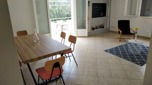 En moderne stue med et træspisebord, røde og sorte stole, en blå gulvtæppe med mønster og en sort stol med en gul vase med blomster.