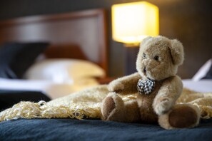 Un ours en peluche est posé sur un lit, avec une lampe en arrière-plan.