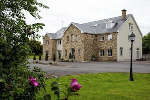 A stone building with a symmetrical facade, multiple windows, and a central entrance.