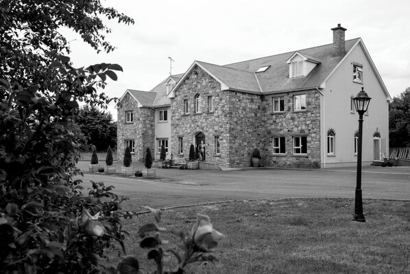 Un bâtiment en pierre doté d’une façade symétrique, de nombreuses fenêtres et d’une entrée centrale.