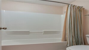 Un baño con bañera, inodoro y cortina de ducha a rayas.