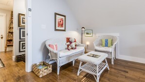 A cozy living room with wicker furniture, a teddy bear, and framed artwork on the wall.