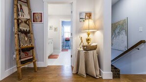 A hallway with a wooden ladder, a table with a lamp, and a map on the wall.