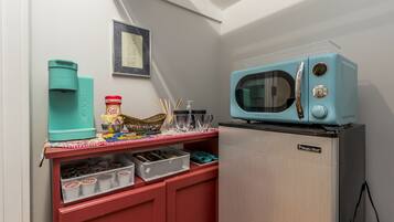 A kitchenette with a teal-colored microwave, a coffee maker, and a small refrigerator.