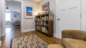 A hallway with a wooden floor, a patterned rug, a bookshelf, and a door.