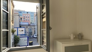 A room with a window overlooking a street, a white cabinet, and a cactus on the windowsill. - L'appart Hyper Centre à 2 pas des Halles (Sète)