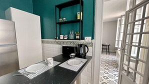 A compact kitchen with a black countertop, white sink, and a teal backsplash. - L'appart Hyper Centre à 2 pas des Halles (Sète)