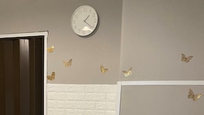 A kitchen with a white refrigerator, a white toaster oven on top, a clock on the wall, and butterfly decals. - Plebiscito's House (Catania)