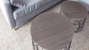 A grey sectional sofa with patterned cushions and two round wooden tables with metal legs. - A 2 PAS DES Plages DE LA Promenade DES Anglais!!!! (Nice)