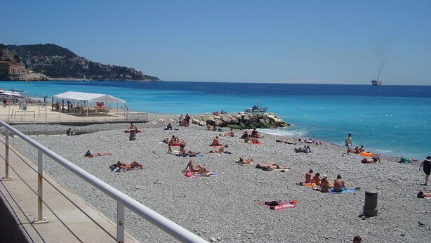 A beach with people sunbathing, a lifeguard tower, and a rocky outcrop. - A 2 PAS DES Plages DE LA Promenade DES Anglais!!!! (Nice)