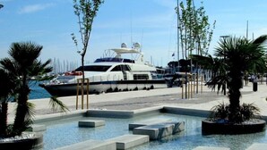 A marina with yachts docked, a swimming pool area, and a modern building in the background. - Modern and Practical Studio in the Heart of Split (Split)