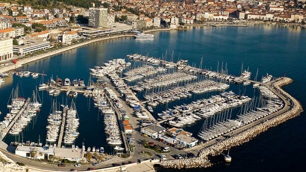 An aerial view of a marina with numerous boats docked, surrounded by a cityscape and mountains in the background. - Modern and Practical Studio in the Heart of Split (Split)