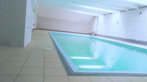 An indoor swimming pool with a tiled floor and walls, a ladder, and a clear water line. - Studio vue sur mer Avec Piscine Interieure (La Panne)