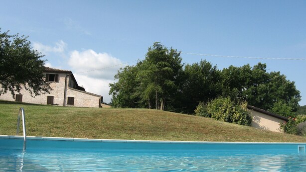 Une piscine avec un bâtiment en pierre en arrière-plan.