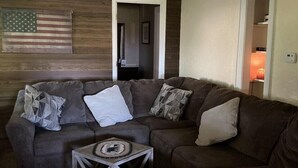 A living room with a sectional sofa, a small coffee table, and a ceiling fan.