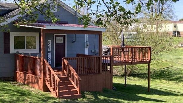 A small house with a wooden porch, a front door, and a 'HOME' sign.