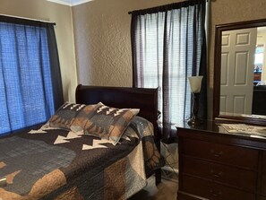 Une chambre à coucher avec un lit, une commode, un miroir et des rideaux.