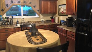 A kitchen with wooden cabinets, a granite countertop, a sink, a coffee maker, and a refrigerator.