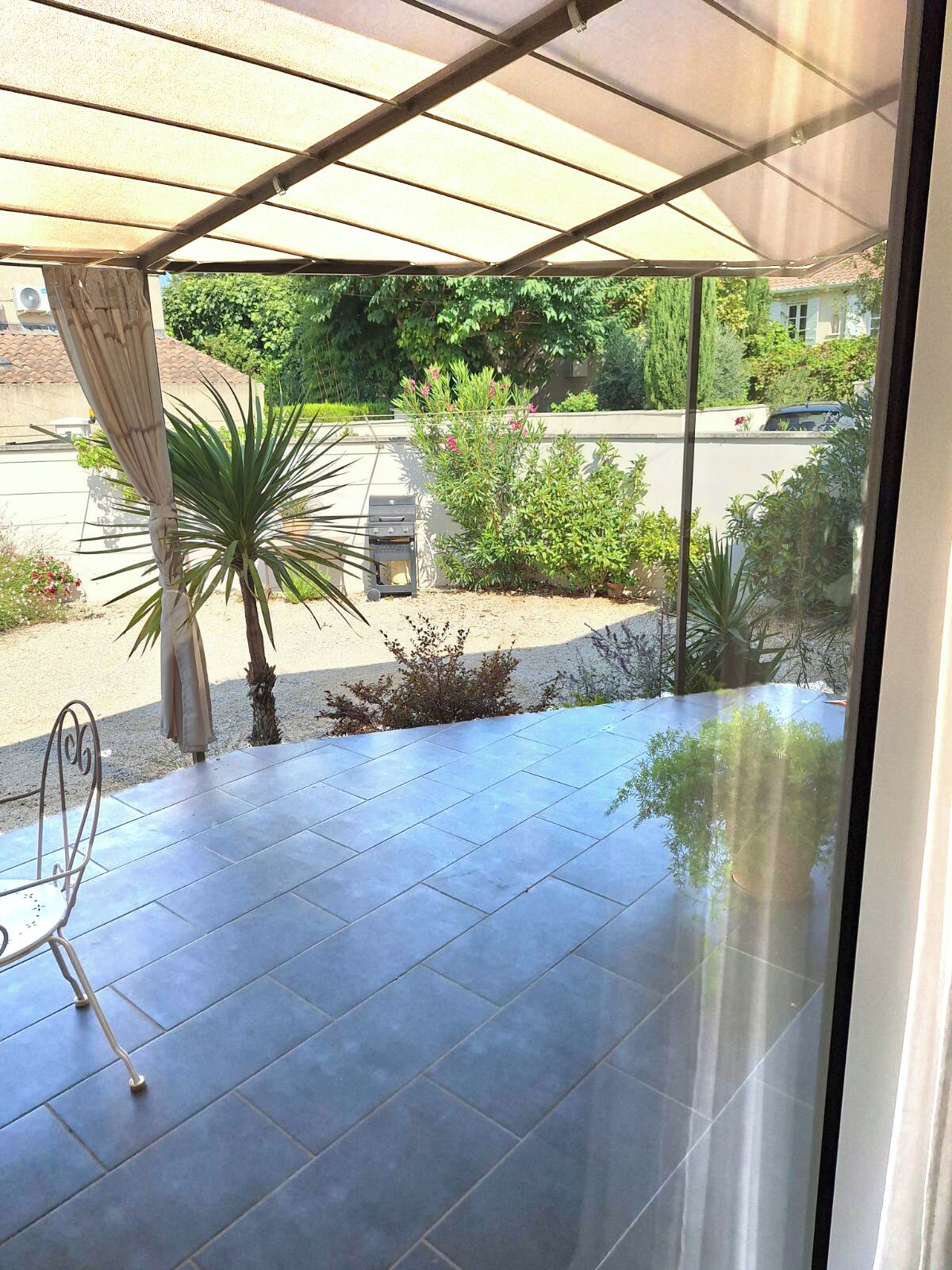 En overdækket patio med grill, plantekasser og udsigt til gaden.