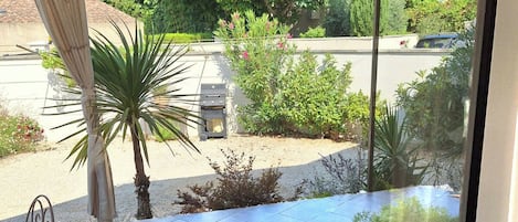En overdækket patio med grill, plantekasser og udsigt til gaden.