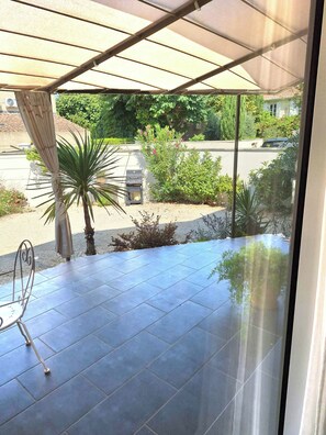 A covered patio area with a grill, potted plants, and a view of the street. - LA Magdeleine (Cabannes)