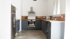 A compact kitchen with a refrigerator, oven, microwave, and washing machine. - LA Magdeleine (Cabannes)