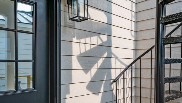 A modern exterior with a black door, a metal staircase, and a lantern.