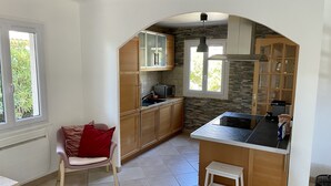 A kitchen with wooden cabinets, a microwave, and a small stool.