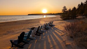 A beach with rows of chairs facing the ocean, a clear sky, and a sunset.