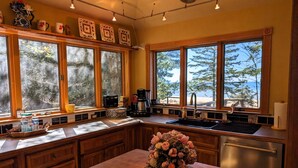 A kitchen with large windows, wooden cabinets, and a central island with a floral arrangement.