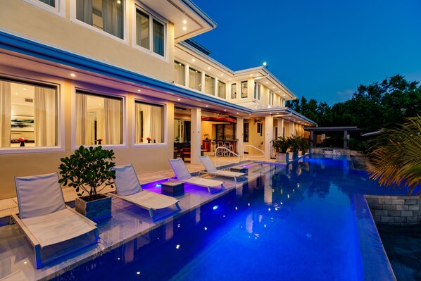 Una casa moderna con piscina, mobiliario exterior y un interior bien iluminado.