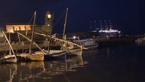 A harbor at night with boats docked, a building with a tower, and a large ship in the background. - Maison typique catalane (Collioure)