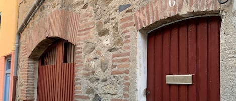 A stone building with two red doors, one with a metal plate above it.