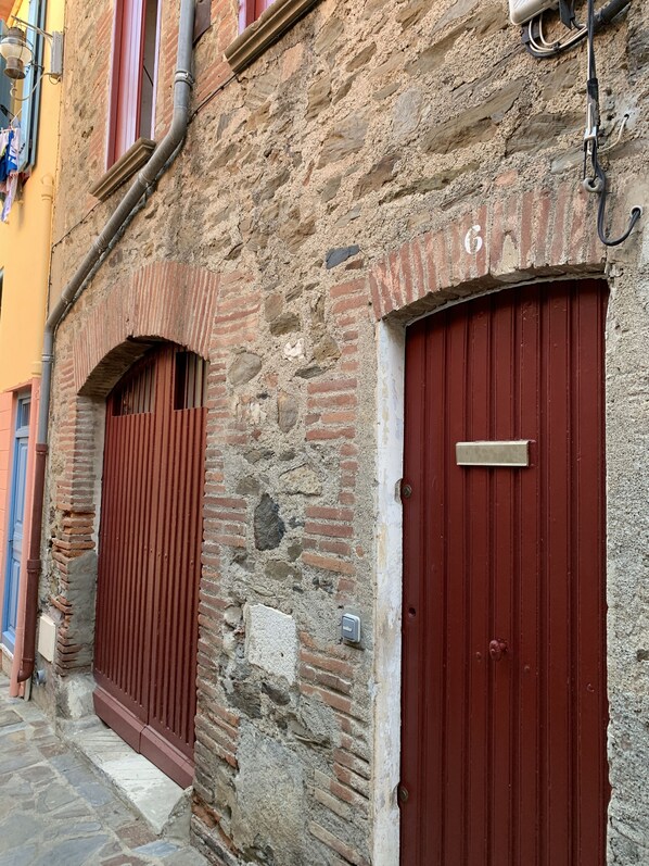 A stone building with two red doors, one with a metal plate above it.