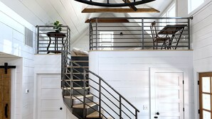 A spacious interior with a central staircase, white walls, and a wooden floor.