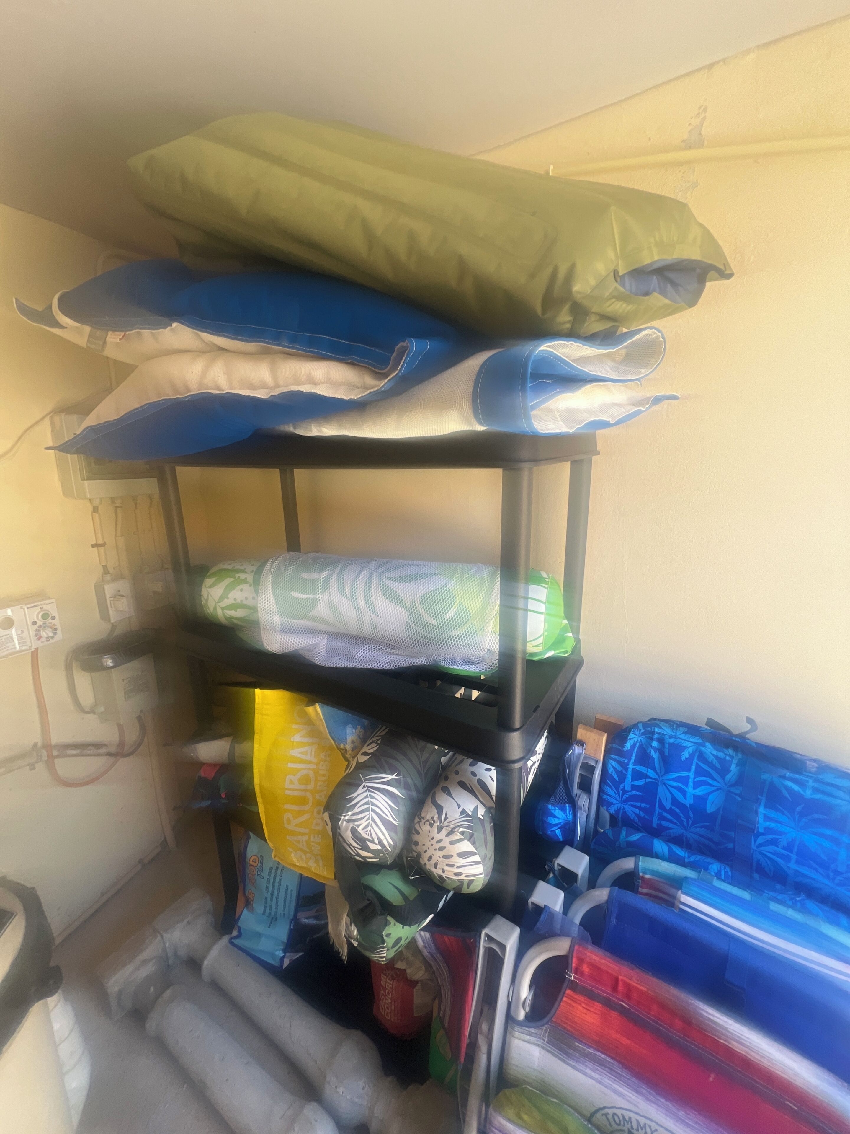 A storage rack with various items including pillows, a mesh bag, and rolled-up mats.