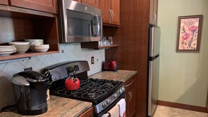 Una cocina con electrodomésticos de acero inoxidable, estufa a gas, microondas y tostadora.