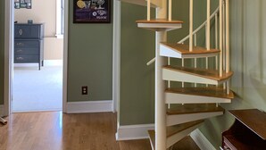 Una escalera de caracol con barandillas blancas y escalones de madera, que conduce a un piso superior.