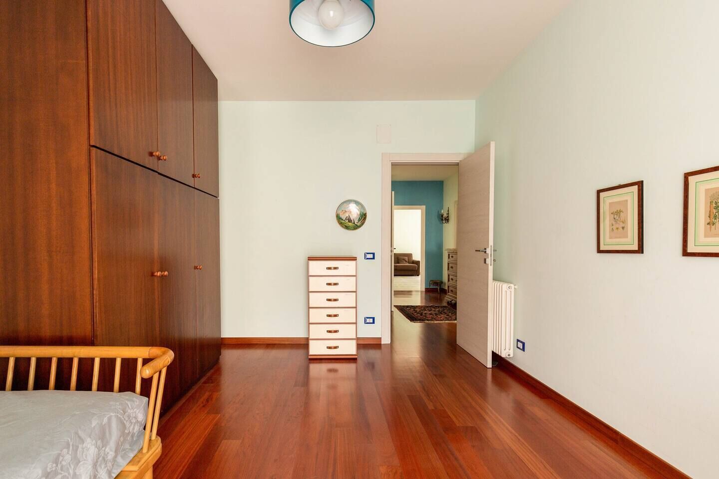 Ein Schlafzimmer mit einem Holfischschrank, einem Nachttisch, einer Holzkommode und einem Bett.