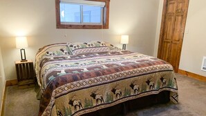 Une chambre à coucher avec un grand lit, deux lampes de chevet, une fenêtre et une porte en bois.