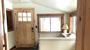 Une cuisine spacieuse et bien éclairée, dotée d’une grande fenêtre, d’une porte en bois et d’un comptoir sur lequel est pos ée une lampe.